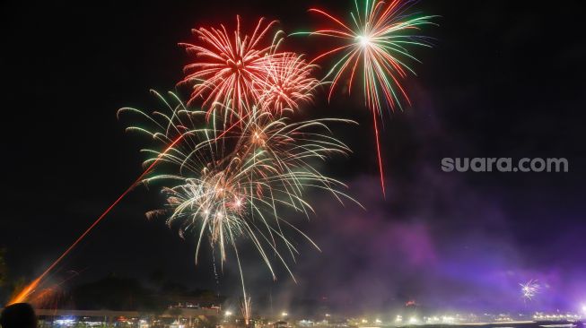 Warga menyaksikan pesta kembang api saat perayaan malam Tahun Baru 2023 di Danau Archipelago, Taman Mini Indonesia Indah (TMII), Jakarta Timur, Minggu (1/1/2023). [Suara.com/Alfian Winanto]