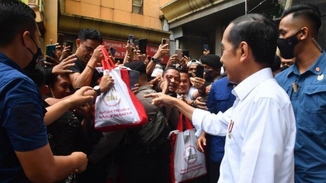 Presiden Joko Widodo atau Jokowi membagikan bansos ketika meninjau Pasar Tanah Abang, Ibukota Pusat, Mulai Pekan (2/1/2023). [Foto: Rusman - Biro Pers Sekretariat PresidenTindakan]