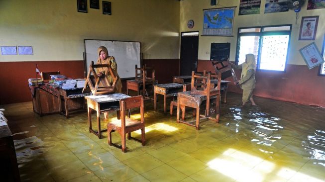 Guru mengecek ruang kelas sekolah yang terdampak banjir di SDN 3 Jati, Kudus, Jawa Tengah, Senin (2/1/2023). [ANTARA FOTO/Yusuf Nugroho].