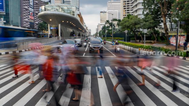 Pekerja melintas saat jam pulang kerja di Kawasan Sudirman - Thamrin, Jakarta Pusat, Senin (2/1/2023). [Suara.com/Alfian Winanto] 