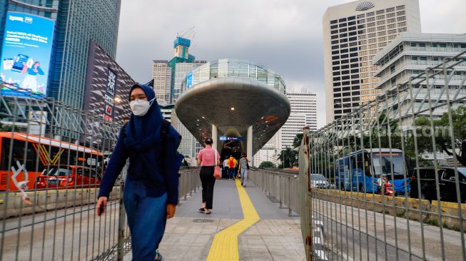 Pekerja melintas saat jam pulang kerja di Kawasan Sudirman - Thamrin, Jakarta Pusat, Senin (2/1/2023). [Suara.com/Alfian Winanto] 