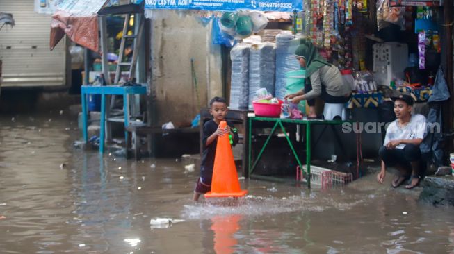 Warga beraktivitas saat banjir di Jalan Kemang Utara IX, Jakarta Selatan, Rabu (4/1/2023). [Suara.com/Alfian Wina Winanto]