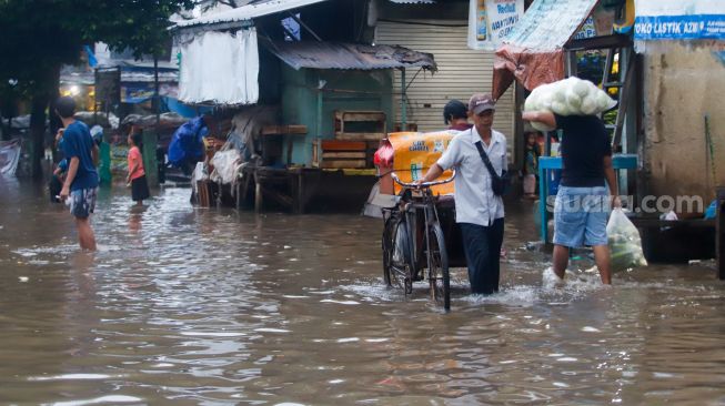 Warga berjalan melewati banjir di Jalan Kemang Utara IX, Jakarta Selatan, Rabu (4/1/2023). [Suara.com/Alfian Wina Winanto]