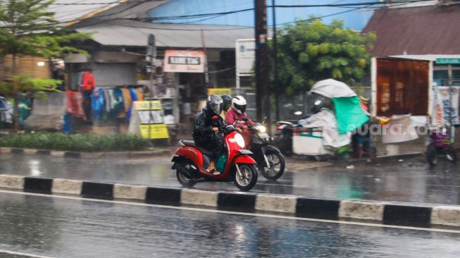 Pengendara motor nelintas saat hujan lebat di kawasan Cililitan, Jakarta Timur, Rabu (4/1/2023). [Suara.com/Alfian Winanto]