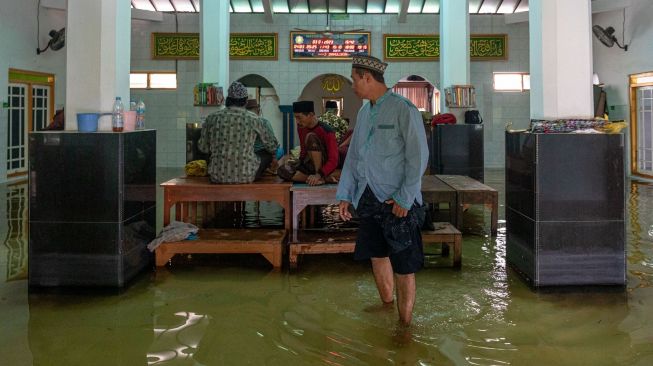 Sejumlah warga melaksankan Salat Asar berjamaah di atas meja yang diletakkan di lantai Masjid Jami Al Muttaqin yang terendam banjir di Desa Prampelan, Kecamatan Sayung, Kabupaten Demak, Jawa Tengah, Selasa, (3/1/2023). [ANTARA FOTO/Aji Styawan].