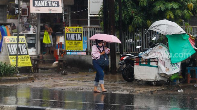 Warga berjalan menggunakan payung saat hujan lebat di kawasan Cililitan, Jakarta Timur, Rabu (4/1/2023). [Suara.com/Alfian Winanto]