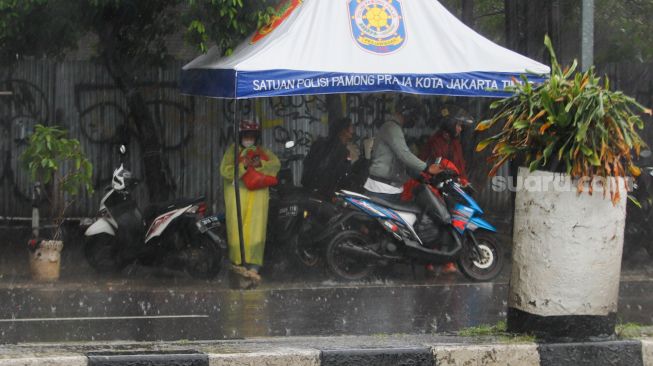 Warga berteduh saat hujan lebat di kawasan Cililitan, Jakarta Timur, Rabu (4/1/2023). [Suara.com/Alfian Winanto]