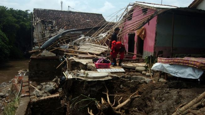 Petugas dan warga membersihkan puing-puing rumah yang hancur diterjang banjir bandang di Desa Kemiriamba, Jatibarang, Brebes, Jawa Tengah, Kamis (5/1/2023). [ANTARA FOTO/Oky Lukmansyah]