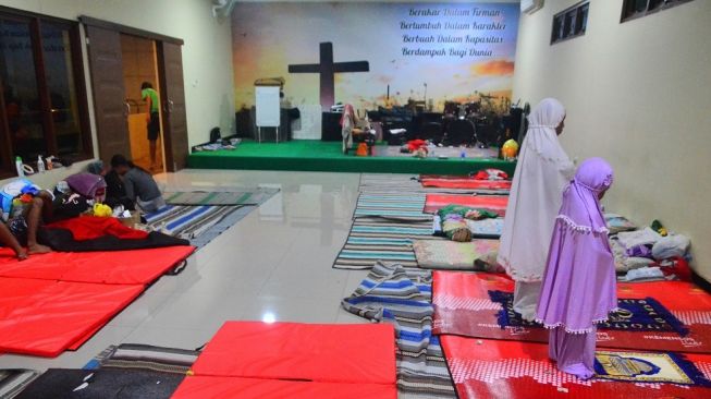 Pengungsi korban banjir melakukan shalat di ruang aula Gereja Kristen Muria Indonesia (GKMI) Tanjung Karang, Kudus, Jawa Tengah, Rabu (4/1/2023). [ANTARA FOTO/Yusuf Nugroho]