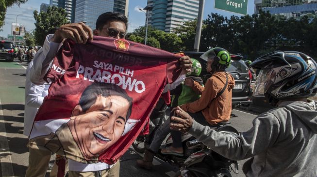 Sejumlah kader Gerindra membagikan kaos dukungan untuk Ketua Umum Partai Gerindra Prabowo Subianto sebagai calon presiden pada Pilpres 2024 kepada pengguna jalan raya di Kantor Badan Pemenangan Presiden Partai Gerindra, Jakarta, Sabtu (7/1/2023). [ANTARA FOTO/Muhammad Adimaja].