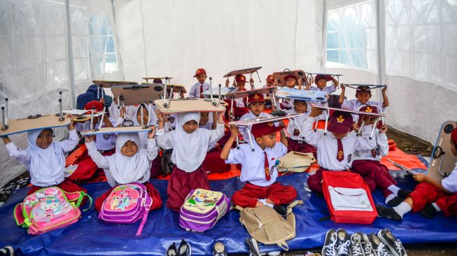 Sejumlah siswa melakukan simulasi gempa saat kegiatan belajar mengajar di tenda sekolah darurat di SDN Citamiang, Sarongge, Kabupaten Cianjur, Jawa Barat, Senin (9/1/2023). [ANTARA FOTO/Raisan Al Farisi/hp]