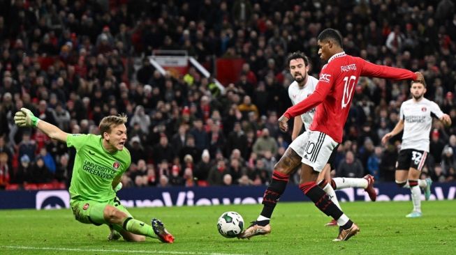 Penyerang Manchester United, Marcus Rashford mencetak gol kedua timnya dengan menaklukan kiper Charlton Ashley Maynard-Brewer (kiri) selama perempat final Piala Liga Inggris antara Manchester United vs Charlton Athletic, di Old Trafford, di Manchester, utara- Inggris barat pada 10 Januari 2023.Oli SCARFF/AFP