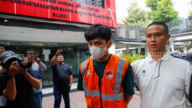 Aktor Revaldo Fifaldi dibawa petugas untuk dihadirkan saat rilis kasus narkoba yang menjeratnya di Polda Metro Jaya, Jakarta, Jumat (13/1/2023). [Suara.com/Alfian Winanto]