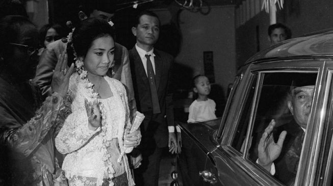 Presiden RI pertama Soekarno melambaikan tangan di dalam mobil seusai menghadiri pernikahan putrinya Rachmawati Soekarnoputri (kedua kiri) dan suami Martomo Pariatman Marzuki (ketiga kiri) di kediaman Ibu Fatmawati, Bengkulu (14/3/1969). [ANTARA FOTO]