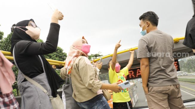 Warga saat menaiki bus tingkat Transjakarta dengan atap terbuka di Jakarta, Sabtu (14/1/2023). [Suara.com/Alfian Winanto]