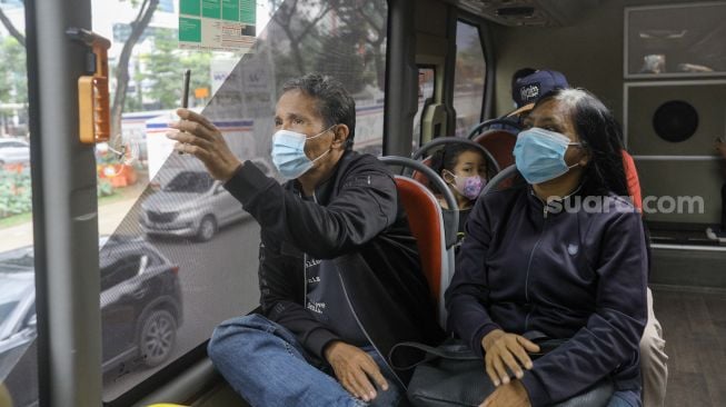 Warga saat menaiki bus tingkat Transjakarta dengan atap terbuka di Jakarta, Sabtu (14/1/2023). [Suara.com/Alfian Winanto]