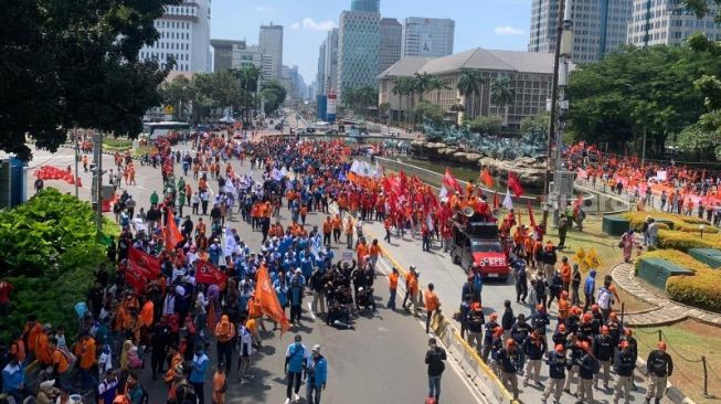 Massa aksi dari Partai Buruh dan beberapa serikat buruh lainnya tiba di area Bundaran Patung Kuda Arjuna, Jakarta Pusat untuk menggelar unjuk rasa tolak Perppu Cipta Kerja, Sabtu (14/1/2023). (Suara.com/Rakha)