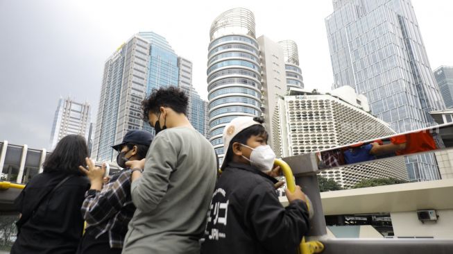 Warga saat menaiki bus tingkat Transjakarta dengan atap terbuka di Jakarta, Sabtu (14/1/2023). [Suara.com/Alfian Winanto]