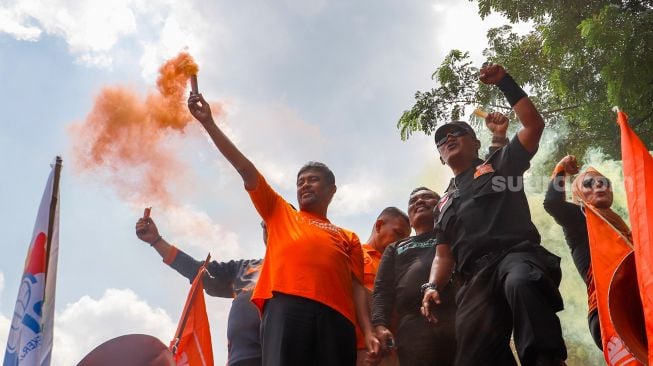 Presiden Partai Buruh Said Iqbal menyalakan flare saat memimpin massa aksi di Kawasan Patung Kuda Arjuna, Jakarta Pusat, Sabtu (14/1/2023). [Suara.com/Alfian Winanto]