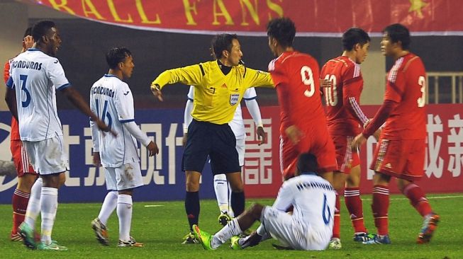 Wasit Lida Jumpei (Tengah) dari Jepang memecah konfrontasi antara pemain dari Honduras dan China selama pertandingan persahabatan sepak bola di Xian pada 18 November 2014. CHINA OUT AFP PHOTOSTR/AFP