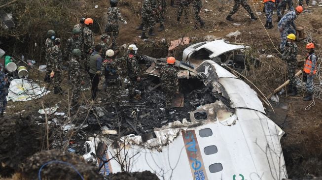 Tim penyelamat memeriksa puing-puing di lokasi kecelakaan pesawat Yeti Airlines di Pokhara, Nepal, Senin (16/1/2023). [PRAKASH MATHEMA/AFP]