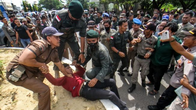 Petugas Satpol PP berusaha mengamankan salah satu pedagang saat akan dilakukan penertiban dan pembongkaran bangunan pedagang di Jalan Stadion Tunas Bangsa, Desa Mon Geudong, Lhokseumawe, Aceh, Senin (16/1/2023). [ANTARA FOTO/Rahmad].