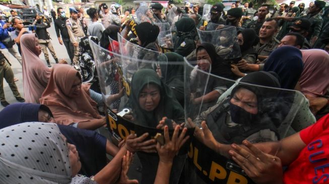 Sejumlah pedagang saling dorong dengan petugas Satpol PP yang akan melkukan penertiban dan pembongkaran bangunan pedagang di Jalan Dtadion Tunas Bangsa, Desa Mon Geudong, Lhokseumawe, Aceh, Senin (16/1/2023). [ANTARA FOTO/Rahmad].