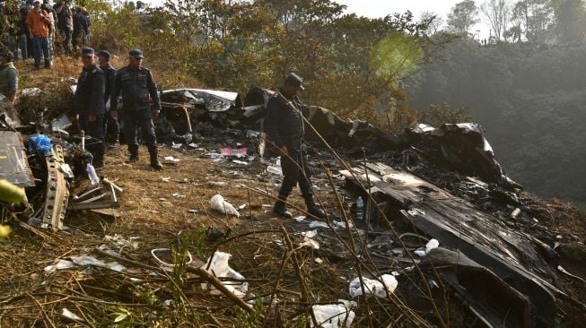 Tim penyelamat memeriksa puing-puing di lokasi kecelakaan pesawat Yeti Airlines di Pokhara, Nepal, Minggu (15/1/2023). [PRAKASH MATHEMA/AFP]
