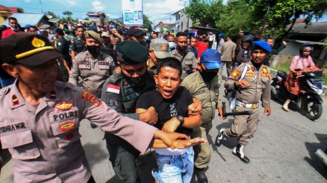 Petugas Satpol PP berusaha mengamankan salah satu pedagang saat akan dilakukan penertiban dan pembongkaran bangunan pedagang di Jalan Stadion Tunas Bangsa, Desa Mon Geudong, Lhokseumawe, Aceh, Senin (16/1/2023). [ANTARA FOTO/Rahmad]