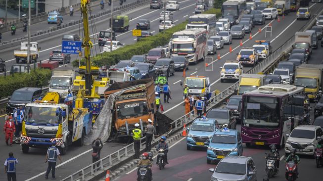 Petugas melakukan evakuasi truk bermuatan batu bara yang mengalami kecelakaan beruntun di Jalan Tol Dalam Kota, Cawang-Grogol KM 5400, di Jakarta, Rabu (18/1/2023). [ANTARA FOTO/Galih Pradipta].