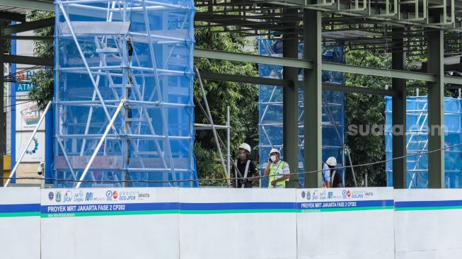 Pekerja menyelesaikan pembangunan Halte TransJakarta di kawasan Jalan Gajah Mada, Jakarta Pusat, Jumat (20/1/2023). [Suara.com/Alfian Winanto]