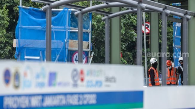 Pekerja menyelesaikan pembangunan Halte TransJakarta di kawasan Jalan Gajah Mada, Jakarta Pusat, Jumat (20/1/2023). [Suara.com/Alfian Winanto]