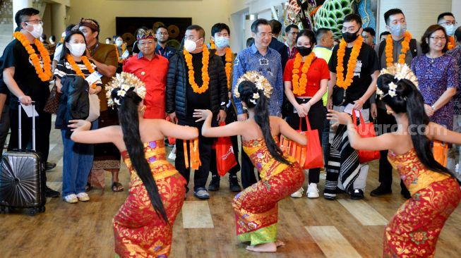 Wisatawan mancanegara asal China disambut tarian tradisional Bali di Terminal Internasional Bandara Internasional I Gusti Ngurah Rai, Badung, Bali, Minggu (22/1/2023). [ANTARA FOTO/Fikri Yusuf/aww]