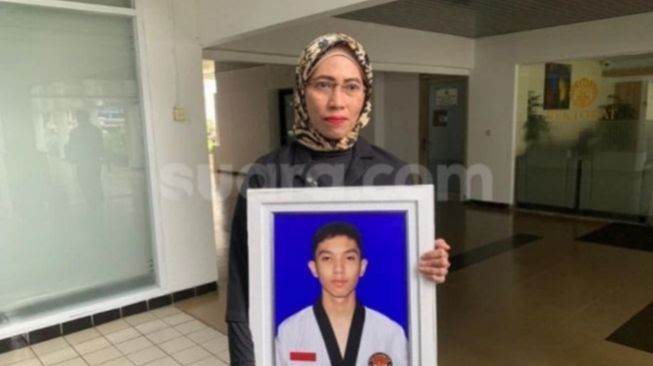 Dwi Syafiera Putri, memegang foto anaknya, Muhammad Hasya Atallah Saputra, mahasiswa UI yang berstatus tersangka usai tewas ditabrak AKBP (Purn) Eko Setia Budi Wahono. (Suara.com/Yaumal)