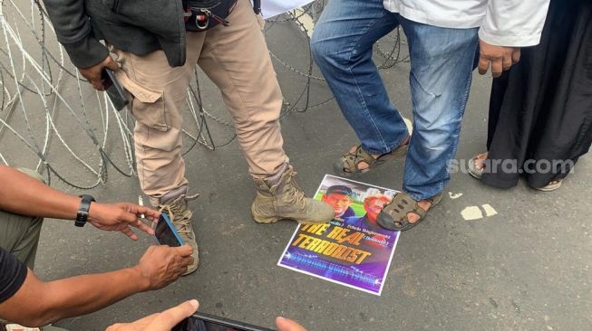 Massa yang tergabung dalam PA 212 injak poster wajah Rasmus Paludan dan Pegida Edwin Wagensveld saat aksi di depan Kedutaan Besar (Kedubes) Swedia, Kuningan, Jakarta Selatan pada Senin (30/1/2023). [Suara.com/Yamual]