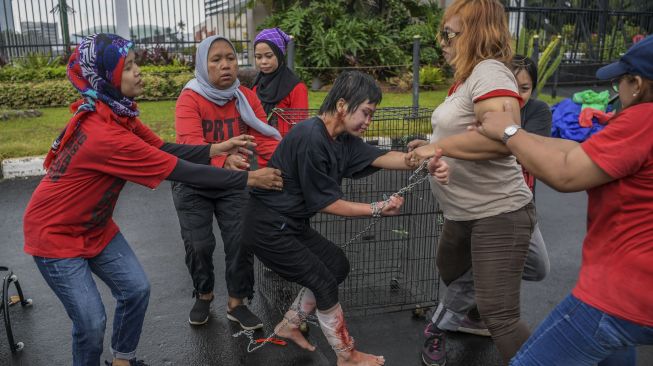 Pengunjuk rasa yang tergabung dalam Koalisi Sipil untuk UU PPRT menggelar aksi teaterikal di depan gedung DPR, Jakarta, Rabu (1/2/2023). [ANTARA FOTO/Galih Pradipta].