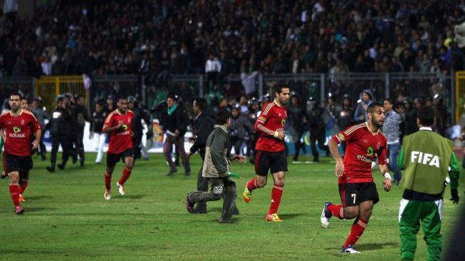 Pemain sepak bola Al-Ahly melarikan diri dari bentrokan antara penggemar setelah pertandingan melawan Al-Masry di Port Said pada 1 Februari 2012. Sedikitnya 74 orang tewas dan ratusan lainnya terluka ketika penggemar saling bentrok menyoroti kekosongan keamanan di Mesir pasca-revolusi. FOTO AFP/STRSTR/AFP.