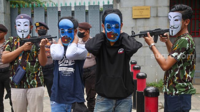 Sejumlah massa yang tergabung dalam Aliansi Mahasiswa Islam (AMI) melakukan aksi teaterika saat unjuk rasa di depan Kedutaan Besar China, Jakarta Selatan, Jumat (3/2/2023). [Suara.com/Alfian Winanto]