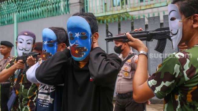 Sejumlah massa yang tergabung dalam Aliansi Mahasiswa Islam (AMI) melakukan aksi teaterika saat unjuk rasa di depan Kedutaan Besar China, Jakarta Selatan, Jumat (3/2/2023). [Suara.com/Alfian Winanto]