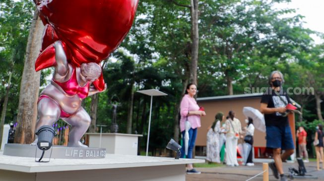 Pengunjung melihat karya seni yang ditampilkan dalam pameran Art Jakarta Gardens 2023 di Hutan Kota Plataran, Senayan, Jakarta Pusat, Selasa (7/2/2023). [Suara.com/Alfian Winanto]