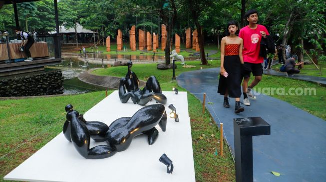 Pengunjung melihat karya seni yang ditampilkan dalam pameran Art Jakarta Gardens 2023 di Hutan Kota Plataran, Senayan, Jakarta Pusat, Selasa (7/2/2023). [Suara.com/Alfian Winanto]