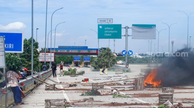 Sejumlah warga melakukan aksi menutup akses jalan menuju Gerbang Tol (GT) Jatikarya 1 dan 2, di ruas Jalan tol Cimanggis-Cibitung, Bekasi, Jawa Barat, Rabu (8/2/2023). [Suara.com/Alfian Winanto]