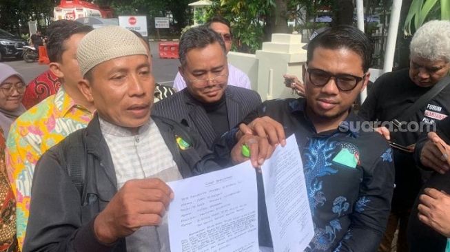 Bripka Madih didampingi 10 pengacara saat mendatangi Polda Metro Jaya. (Suara.com/M Yasir)