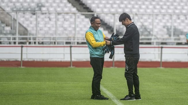 Pelatih Timnas U-20 Shin Tae-yong (kanan) membantu Menteri Pemuda dan Olahraga Zainudin (kiri) memakai sarung tangan penjaga gawang dalam acara 100 Hari Menuju Piala Dunia U-20 Indonesia 2023 di Stadion Utama Gelora Bung Karno, Jakarta, Kamis (9/2/2023). Kementerian Pemuda dan Olahraga bersama Persatuan Sepak Bola Seluruh Indonesia (PSSI) resmi menghitung mundur 100 hari menuju perhelatan Piala Dunia U-20 2023 yang akan berlangsung di Indonesia pada 20 Mei-11 Juni 2023. ANTARA FOTO/Aprillio Akbar/nym. 