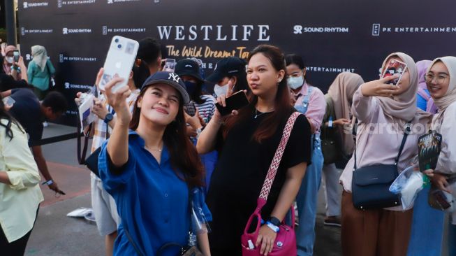 Penonton berswafoto saat menghadiri konser Westlife 'The Wild Dreams Tour' di Stadion Madya, Gelora Bung Karno, Jakarta Pusat, Sabtu (11/2/2023). [Suara.com/Alfian Winanto]