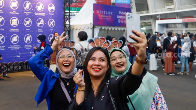 Penonton berswafoto saat menghadiri konser Westlife 'The Wild Dreams Tour' di Stadion Madya, Gelora Bung Karno, Jakarta Pusat, Sabtu (11/2/2023). [Suara.com/Alfian Winanto]