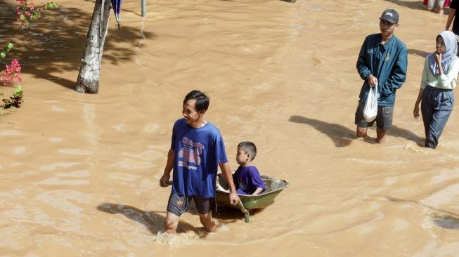 Warga melintasi banjir di Desa Kedawung, Grati, Pasuruan, Jawa Timur, Sabtu (11/2/2023). [ANTARA FOTO/Umarul Faruq].