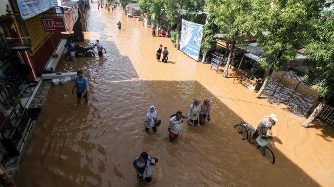 Warga melintasi banjir di Desa Kedawung, Grati, Pasuruan, Jawa Timur, Sabtu (11/2/2023). ANTARA FOTO/Umarul Faruq].