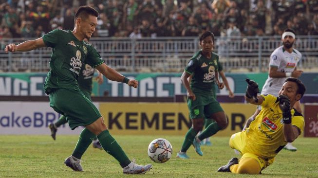 Pesepak bola Persebaya Surabaya Sho Yamamoto (tengah) melakukan tendangan ke arah penjaga gawang PSS Sleman Ega Rizky Pramana (kanan) dalam lanjutan BRI Liga 1 di Stadion Gelora Joko Samudro, Gresik, Jawa Timur, Senin (13/2/2023). Persebaya Surabaya mengalahkan PSS Sleman dengan skor 4-2. ANTARA FOTO/Rizal Hanafi/Zk/rwa. 