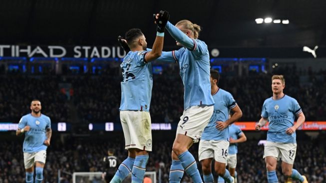 Gelandang Manchester City Riyad Mahrez (kiri tengah) melakukan selebrasi dengan Erling Haaland (kanan tengah) setelah mencetak gol ketiga timnya dari titik penalti selama pertandingan pekan ke-23 Liga Inggris antara Manchester City vs Aston Villa di Stadion Etihad di Manchester , barat laut Inggris, pada 12 Februari 2023.Paul ELLIS / AFP.